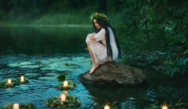 O femeie frumoasă care stă pe marginea unui lac și privește niște lumânări pentru a ilustra una dintre cele trei zodii care nu uită cu ușurință