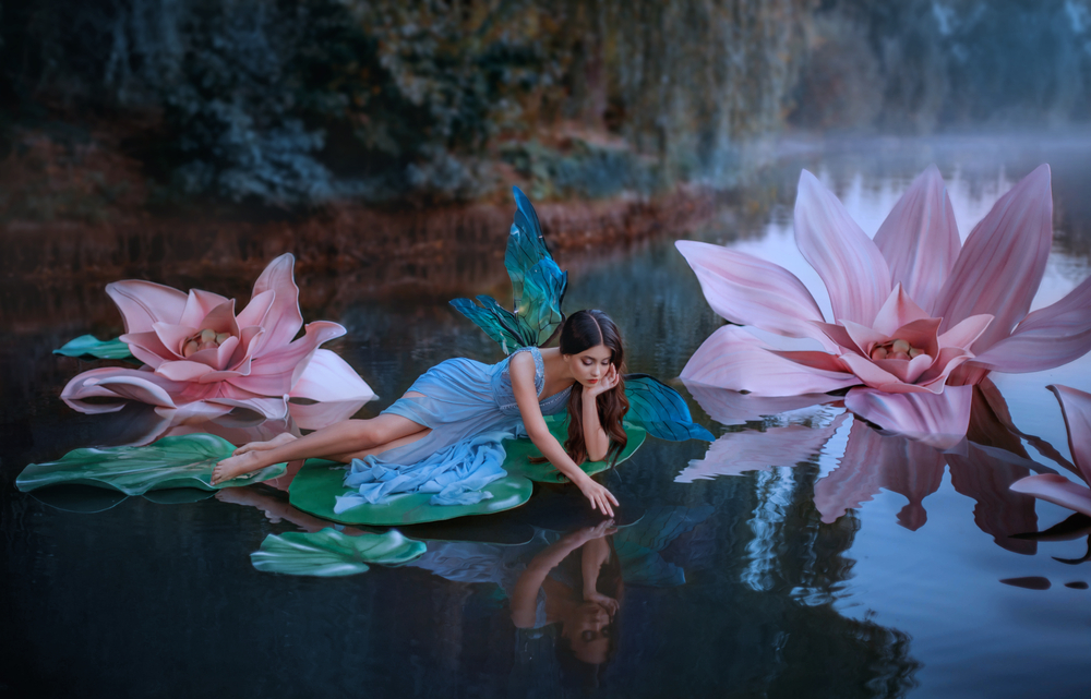 O femeie îmbrăcată în zână, pe o frunză de nufăr, pe un lac