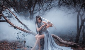 O femeie frumoasă care poartă o rochie gri și stă pe o cracă ținând pe mână o bufniță pentru a ilustra una dintre cele patru zodii care vor să se răzbune