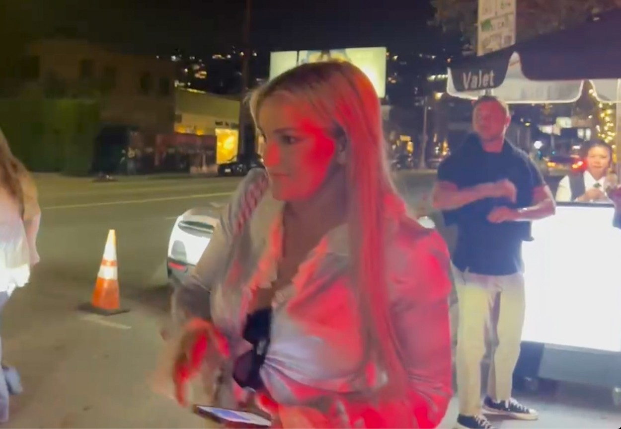 Britney Spears, într-o cămașă albă, într-o parcare, noaptea