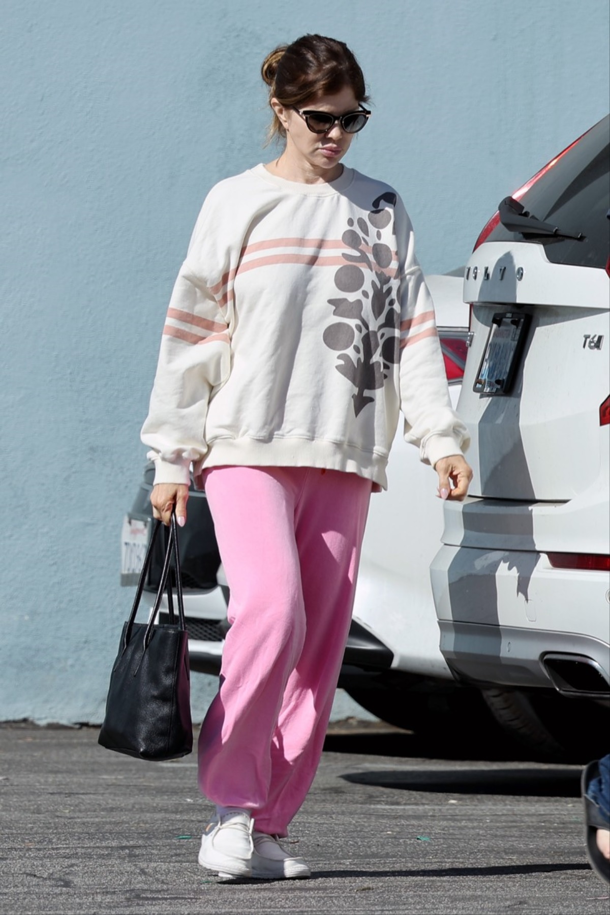 Donna D'Errico într-o bluză albă și o pereche de pantaloni negri într-o parcare din Los Angeles