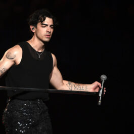 Joe Jonas, pe scenă, în timpul unui concert, în haine negre