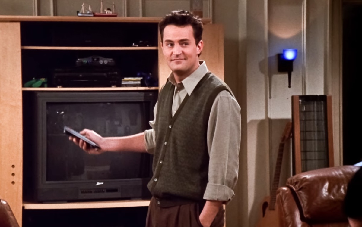 Matthew Perry cu o telecomandă în mână într-o scenă din serialul Friends
