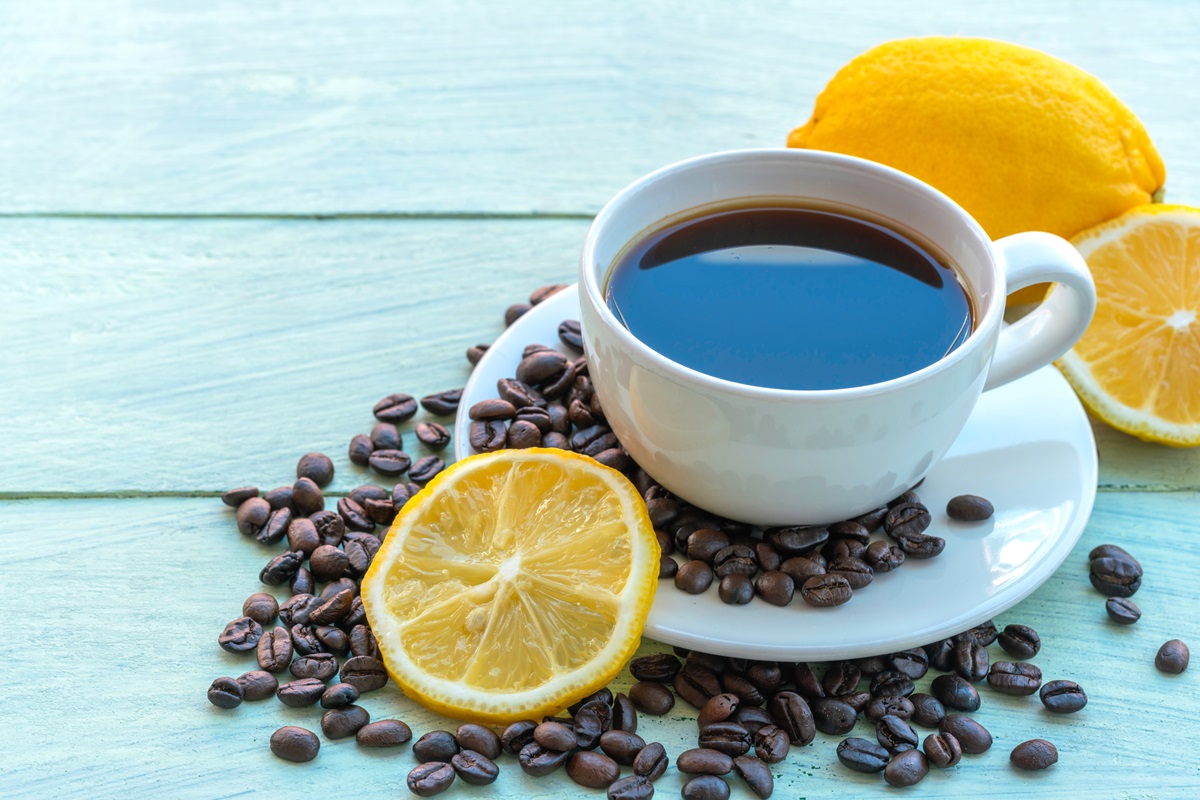 O ceașcă cu cafea cu lămâie pusă alături de o felie de lămâie pentru a ilustra modul în care cafeaua cu lămâie te-ar putea ajuta să slăbești