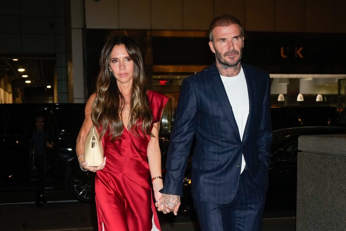 Victoria Beckham într-o rochie roșie alături de David Beckham care poartă costum și se îndreaptă la un restaurant din New York