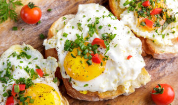 Un mic dejun compus din ouă puse pe pat de pâine, condimente și legume proaspete