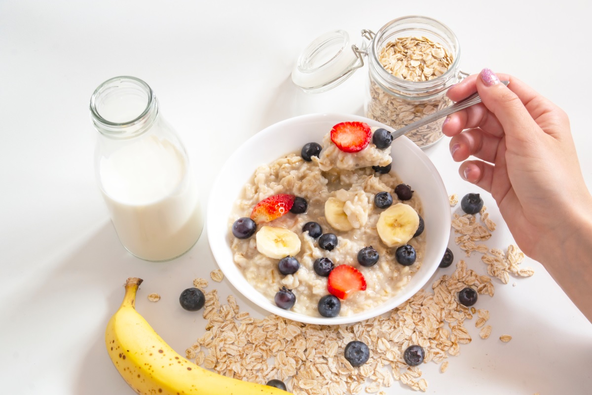 O masă pe care se află un pahar cu lapte, o banană și un bol cu terci de ovăz pentru a ilustra ce se întâmplă dacă mănânci fulgi de ovăz în fiecare dimineață