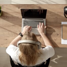 O femeie care stă pe scaun, la birou și lucrează la laptop