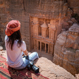 O femeie care vizitează Petra, Iordania și stă așezată pentru a face poze