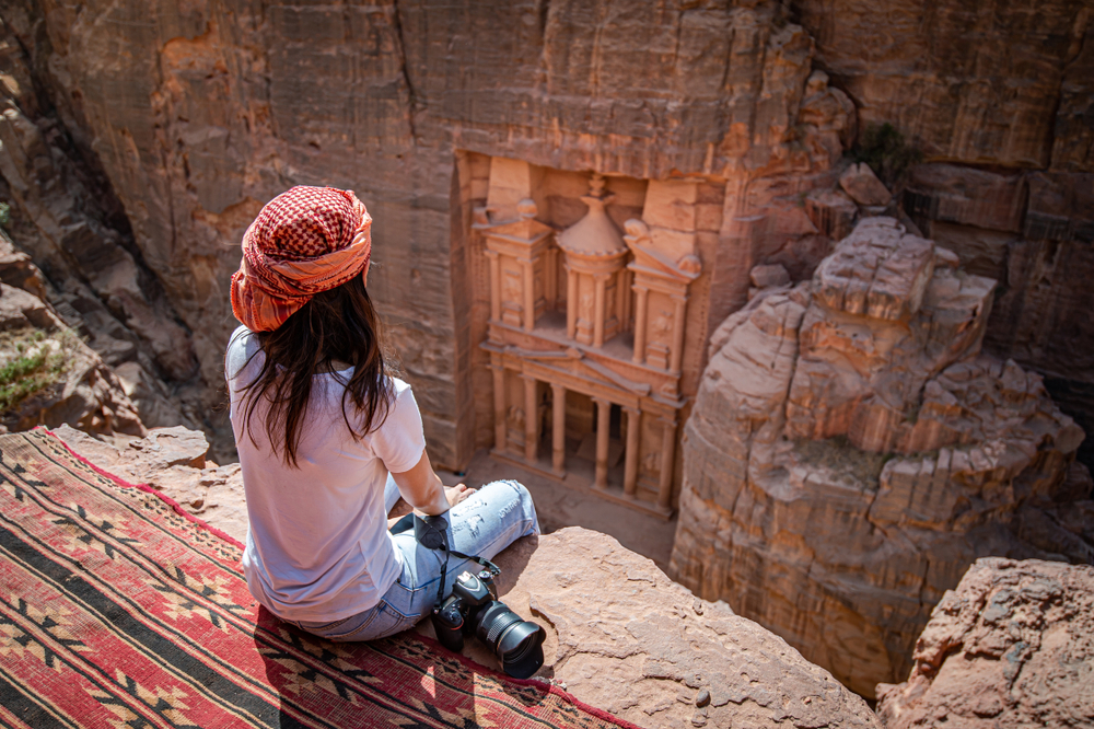 O femeie care vizitează Petra, Iordania și stă așezată pentru a face poze