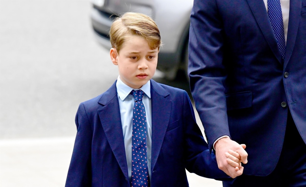 Prințul George, îmbrăcat la costum, în timp ce se plimbă de mână cu tatăl său