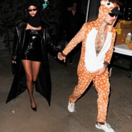 Hailey Bieber într-o rochie din latex, neagră, alături de Justin Bieber care poartă un costum portocaliu de animal la o petrecere de Halloween din 2023