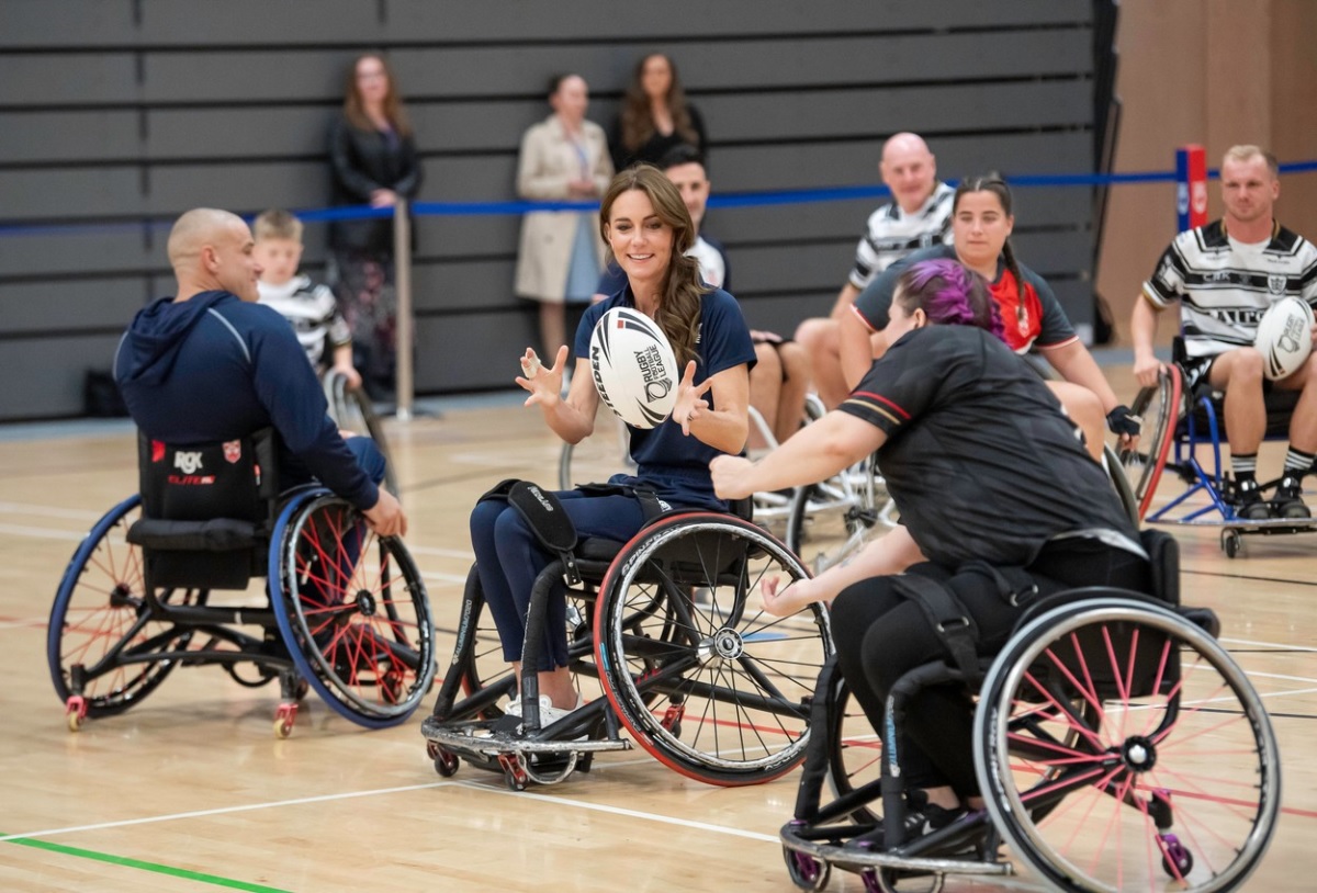 Kate Middleton în timp ce joacă rubgy cu mai mulți jucători care se află în scaun cu rotile