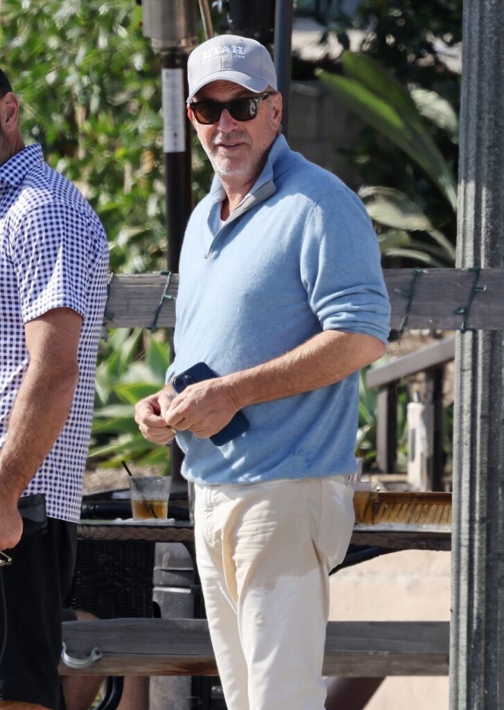 Kevin Costner, la ieșirea dintr-un restaurant, într-o bluză bleu și o pereche de pantaloni albi
