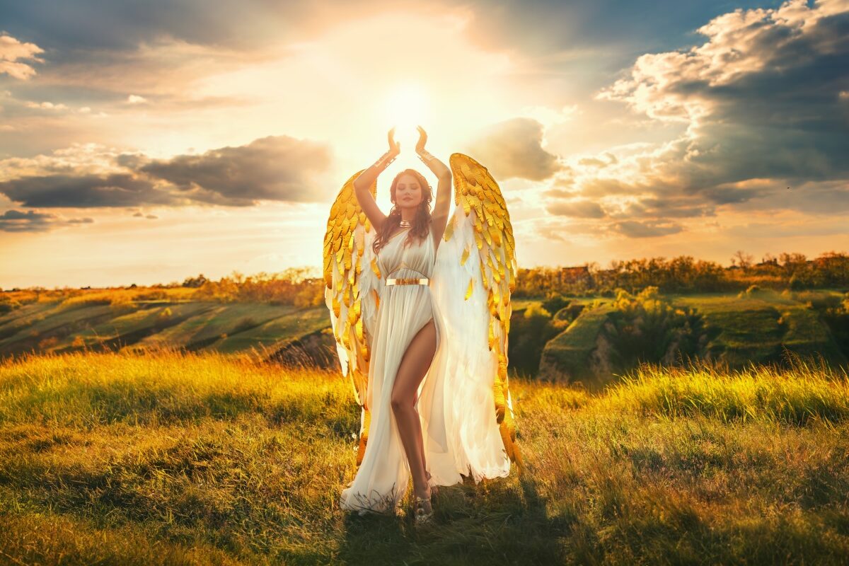 O femeie frumoasă care poartă o rochie albă și are aripi de înger, aurii, pentru a ilustra una dintre cele trei zodii care au parte de căștiguri financiare în luna noimebrie 2023