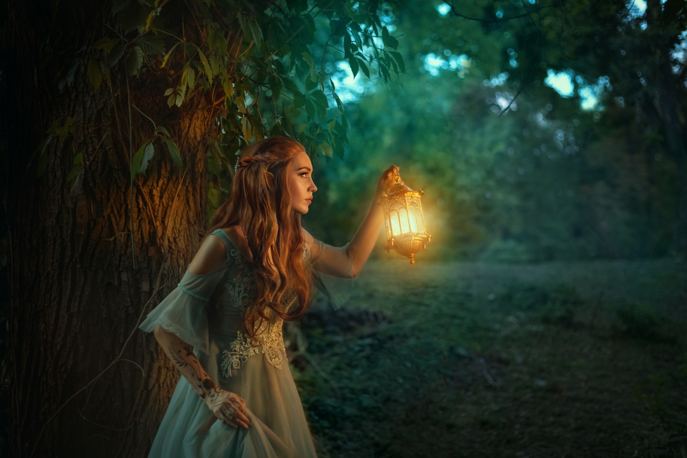 O femeie care luminează cu un felinar în pădure