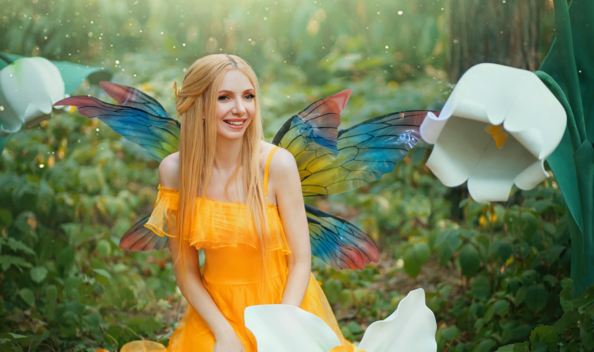 O femeie frumoasă care poartă o rochie galbenă și are aripi de zână, stând printre flori albe, pentru a ilustra una dintre cele patru zodii care se bucură de lucrurile simple