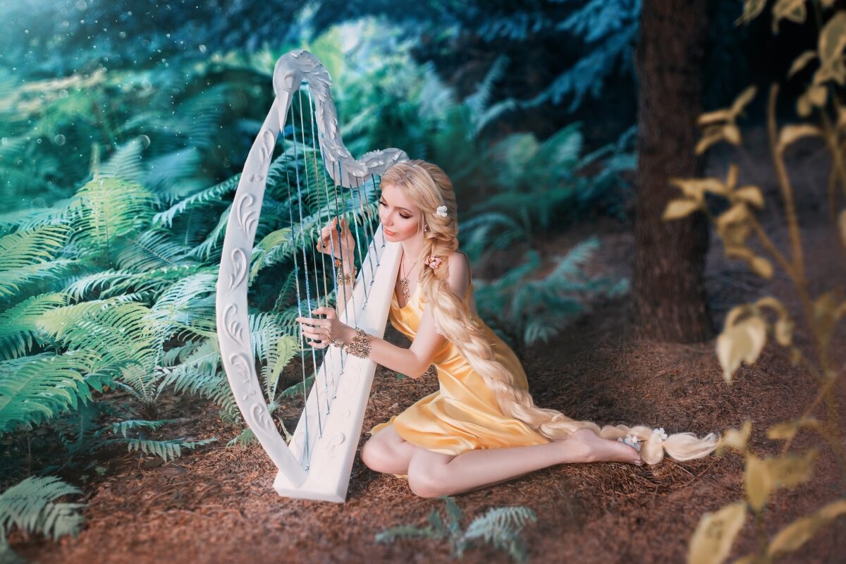 O femeie frumoasă care stă singură într-o pădure și cântă la o harpă pentru a ilustra una dintre cele trei zodii care se despart în ziua de 16 octombrie 2023