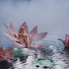 O femeie frumoasă, care stă pe o floare de nufăr, pe un lac întunecat