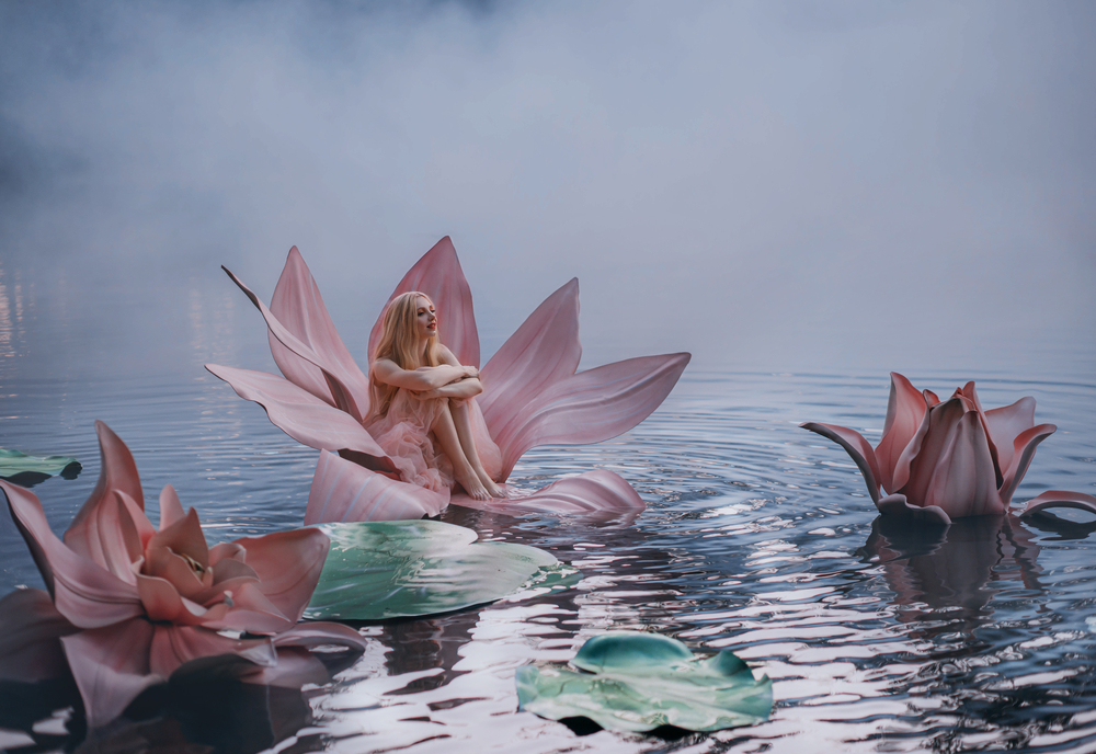 O femeie frumoasă, care stă pe o floare de nufăr, pe un lac întunecat