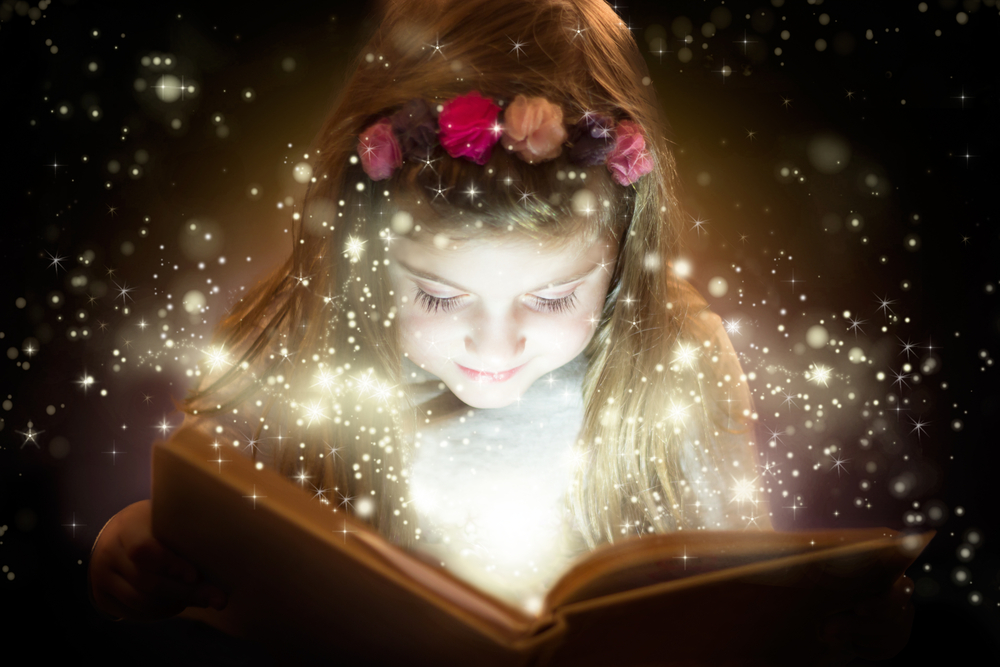 O fetiță care citește dintr-o carte ce pare magică
