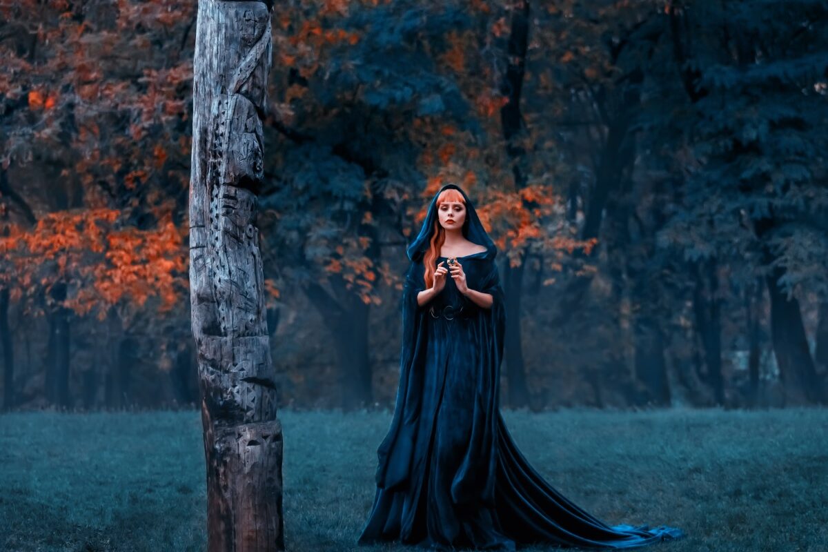 O femeie frumoasă care poartă o rochie neagră și stă singură într-o pădure pentru a ilustra una dintre cele trei zodii ghinioniste în ziua de 30 octombrie 2023