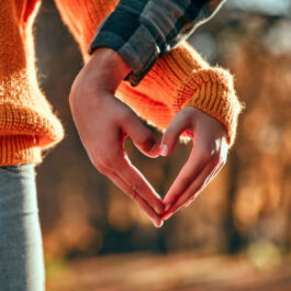 Imagine cu doi îndrăgostiți cărora li se văd mâinile în formă de inimă