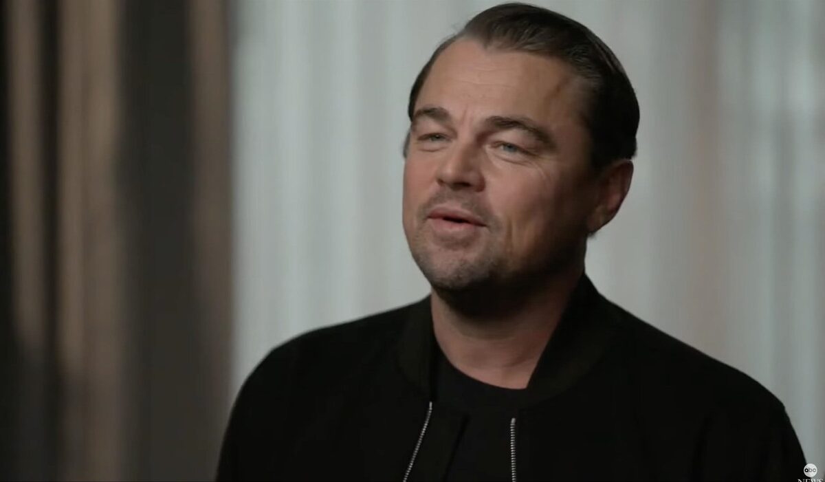 Leonardo DiCaprio, cu zâmbetul pe buze, în haine de culoare neagră
