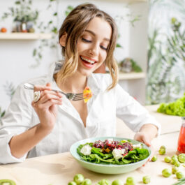 O femeie care mănâncă salată dintr-un bol alb