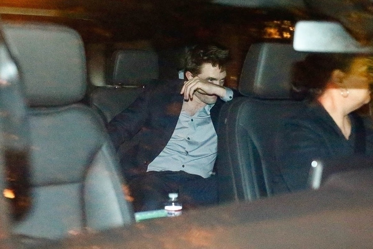 Robert Pattinson în timp ce se ferește de paparazzi într-o mașină