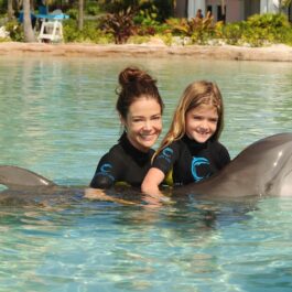 Denise Richards și Sami Sheen în timp ce pozează împreună cu un delfin