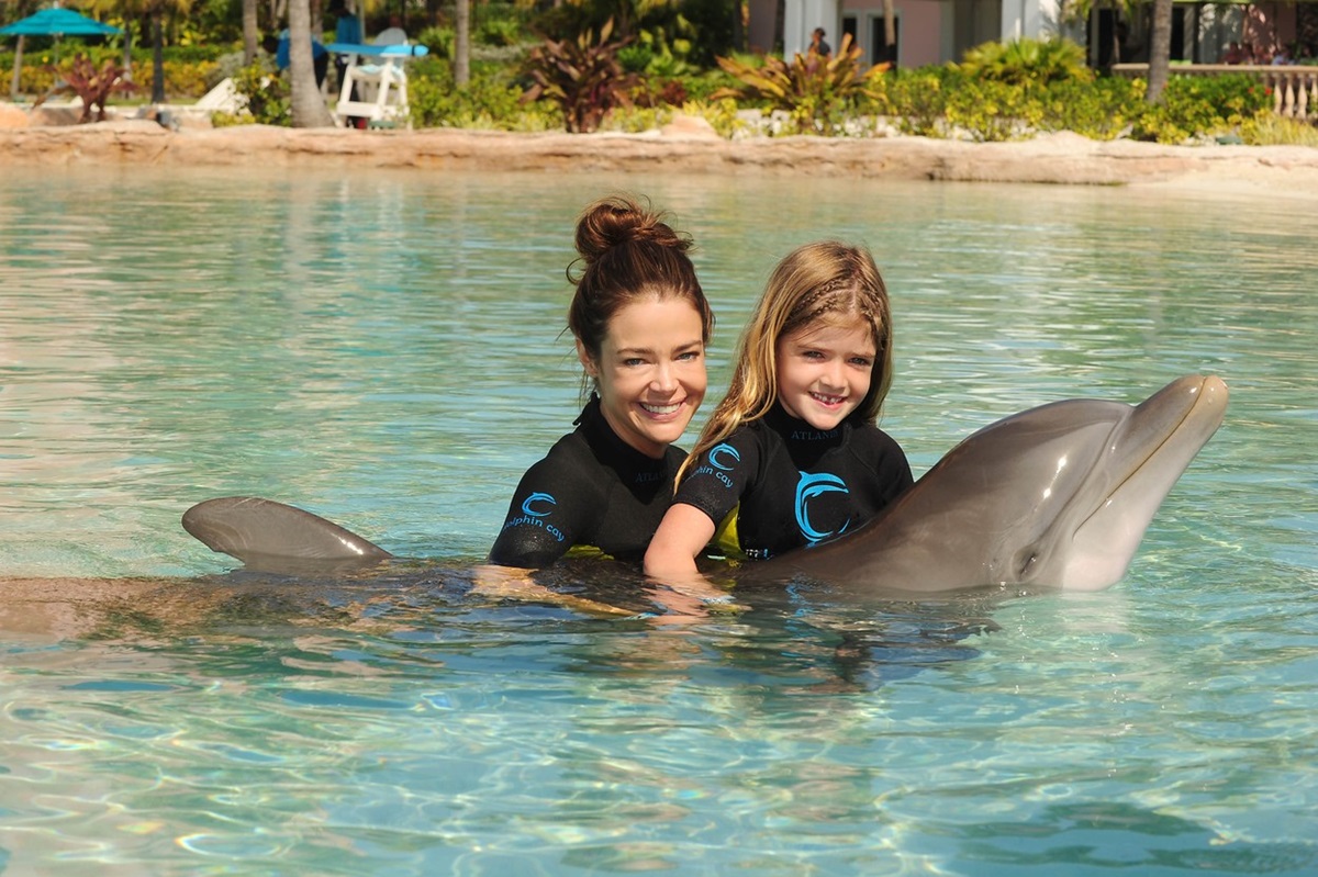 Denise Richards și Sami Sheen în timp ce pozează împreună cu un delfin