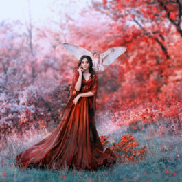 O femeie îmbrăcată într-o rochie elegantă, roșie, într-o pădure