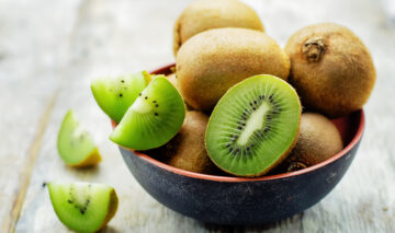 Un castron cu fructe de kiwi fotografiate pe un blat de culoare gri