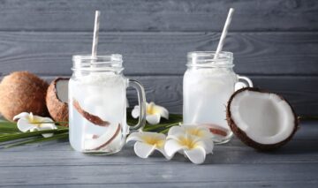 Două pahare pline cu apă de cocos care ajută la îmbunătățirea sănătății organismului