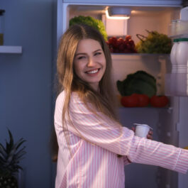 O femeie care deschide frigiderul și vrea să mănânce un iaurt