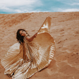 Fată frumoasă îmbrăcată într-o rochie lungă stă în deșert