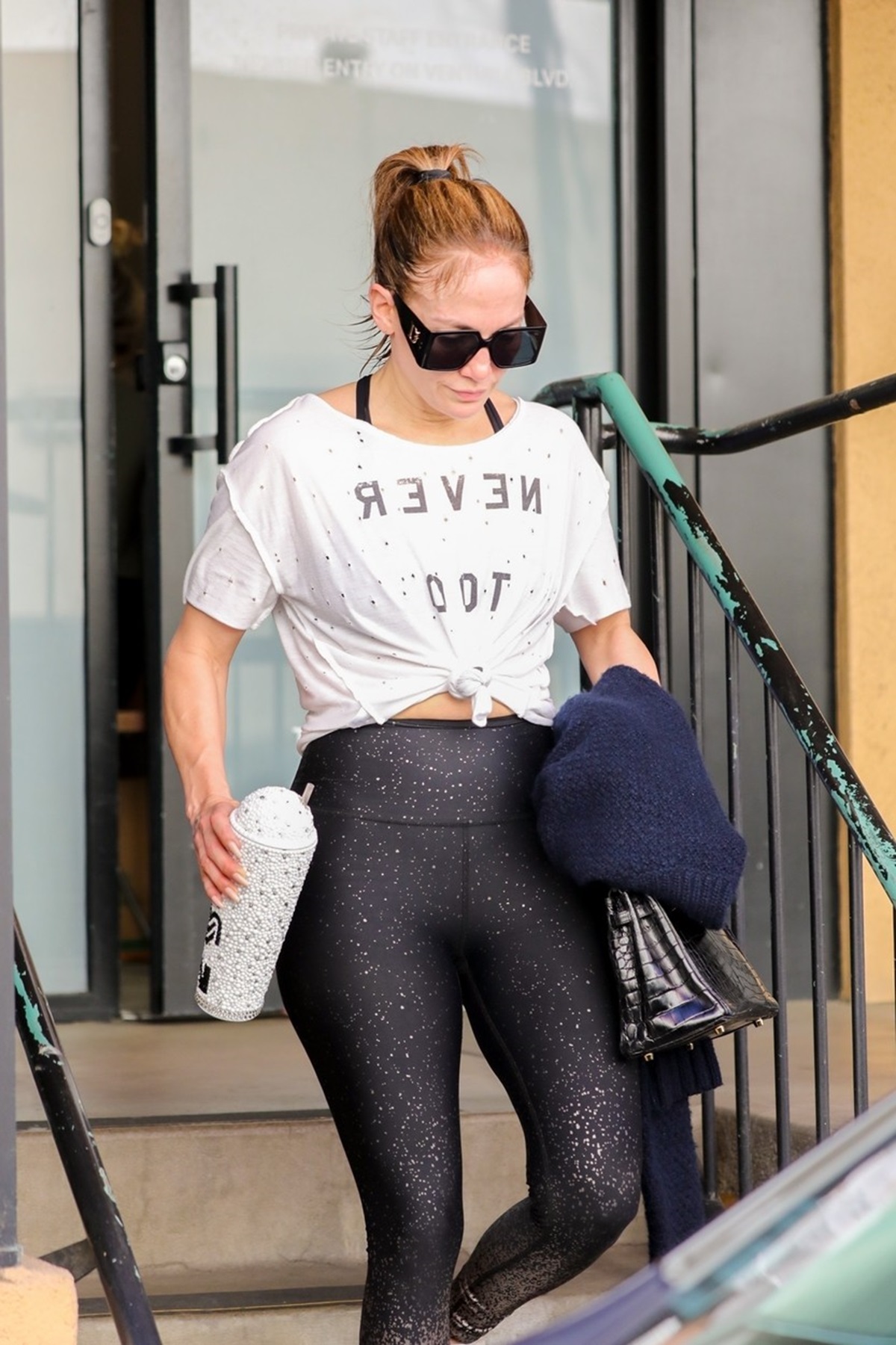 Jennifer Lopez într-un tricou alb și în colanți în timp ce părăsește o sală de sport