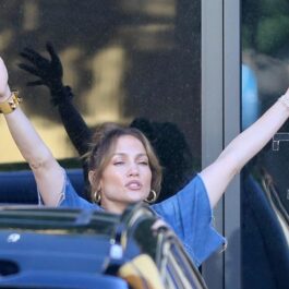 Jennifer Lopez în timp ce întinde mâinile în aer într-o parcare