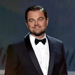Leonardo DiCaprio îmbrăcat la un costum negru cu o cămașă albă în timp ce ține un discurs pe o scenă