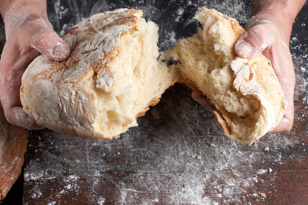 Pâine cu cartofi ruptă în două mâini