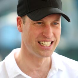 Prințul William, cu o șapcă neagră și un tricou alb, polo