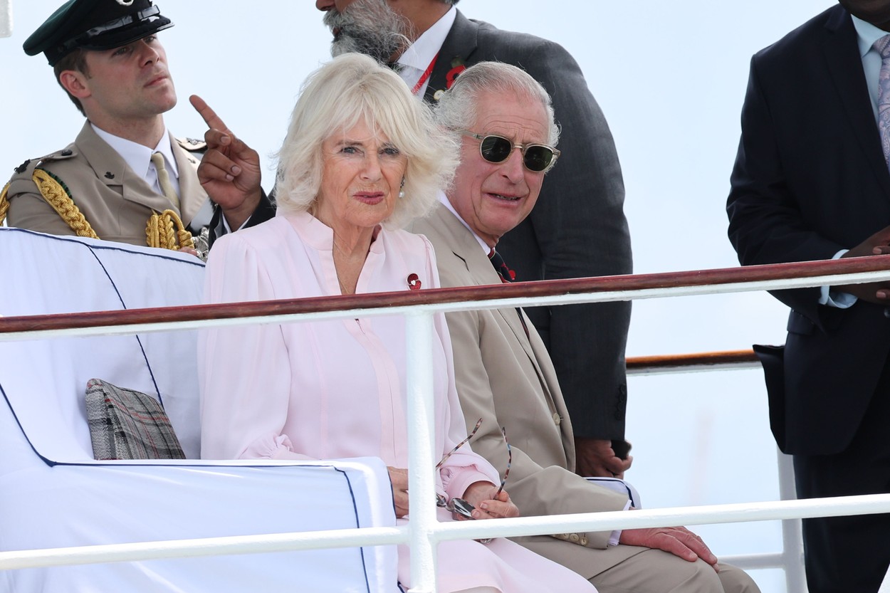 Regina Camilla și Regele Charles în timp ce stau împreună pe o bancă în timpul turneului din Africa