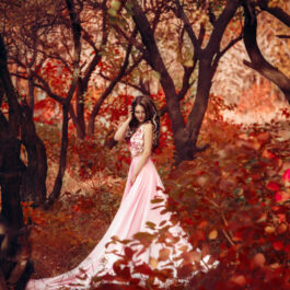 O femeie frumoasă, îmbrăcată într-o rochie luxoasă, în pădure