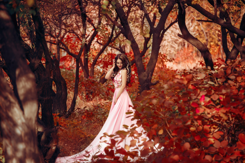 O femeie frumoasă, îmbrăcată într-o rochie luxoasă, în pădure