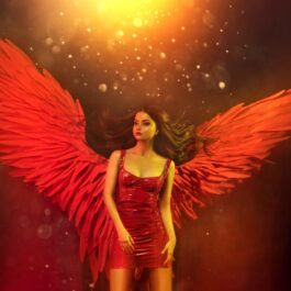 Fată frumoasă îmbrăcată cu o rochie roșie și cu aripi roșii pe un fundal închis la culoare