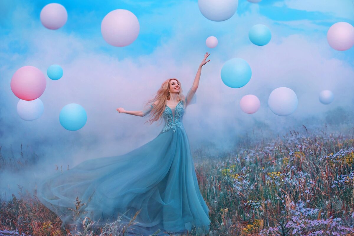 O femeie frumoasă care poartă o rochie albastră și este înconjurată de baloane pentru a ilustra una dintre cele trei zodii care își schimbă norocul în luna noiembrie 2023