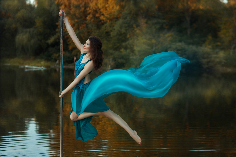 O femeie îmbrăcată într-o rochie turcoaz, care plutește peste un lac