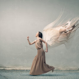 O femeie care se bucură și care are aripi de înger atașate la o rochie crem