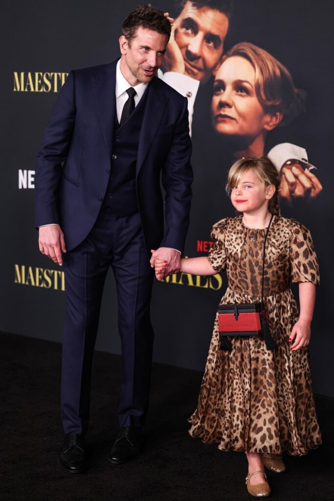 Bradley Cooper, la costum, alături de fiica lui, Lea, care poartă o rochiță cu imprimeu de leopard, la premiera filmului Maestro